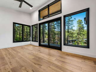 Experience breathtaking views from this stunning modern home, featuring expansive windows that frame the lush forest scenery.