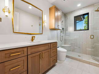 Experience modern luxury in this stunning bathroom, featuring a sleek vanity with gold hardware and a quartz countertop.