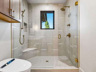 Experience luxury in this modern bathroom featuring a spacious walk-in shower with elegant marble tile and a built-in bench.
