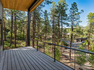 Experience seamless indoor-outdoor living from this stunning modern deck, offering panoramic views of a serene pine forest.