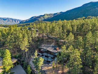 Nestled amidst a lush pine forest, this modern mountain home offers breathtaking panoramic views of the surrounding peaks.