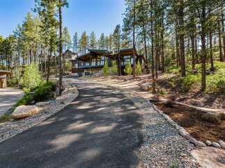 Nestled amidst towering pine trees, this modern mountain home offers a stunning architectural design with expansive windows that capture the natural beauty of its surroundings.
