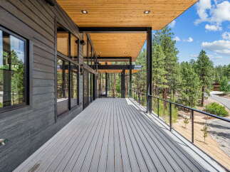 Experience modern living with this stunning home featuring a spacious, covered deck perfect for outdoor entertaining and enjoying the surrounding pine forest views.