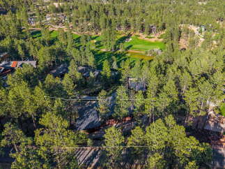 Nestled amidst a lush pine forest, this property offers a serene retreat with a golf course visible in the background.
