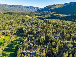 Discover this stunning aerial view of a property nestled within a lush pine forest, adjacent to a pristine golf course.