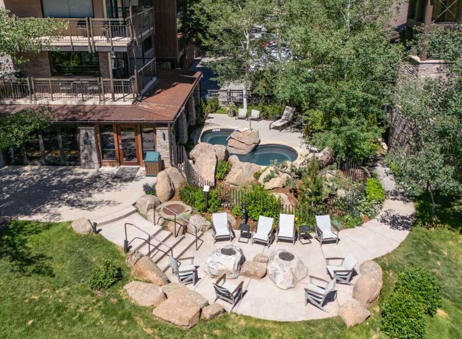 Experience outdoor living at its finest with this property's inviting patio area, featuring comfortable seating, fire pits, and two relaxing hot tubs surrounded by natural rock formations.