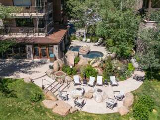 Experience outdoor living at its finest with this property's inviting patio area, featuring comfortable seating, fire pits, and two relaxing hot tubs surrounded by natural rock formations.
