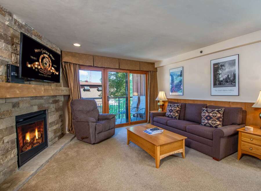 Cozy up by the stone fireplace in this inviting living room, perfect for relaxing after a day on the slopes.