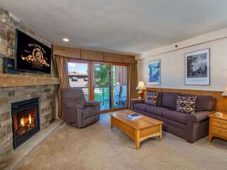 Cozy up by the stone fireplace in this inviting living room, perfect for relaxing after a day on the slopes.