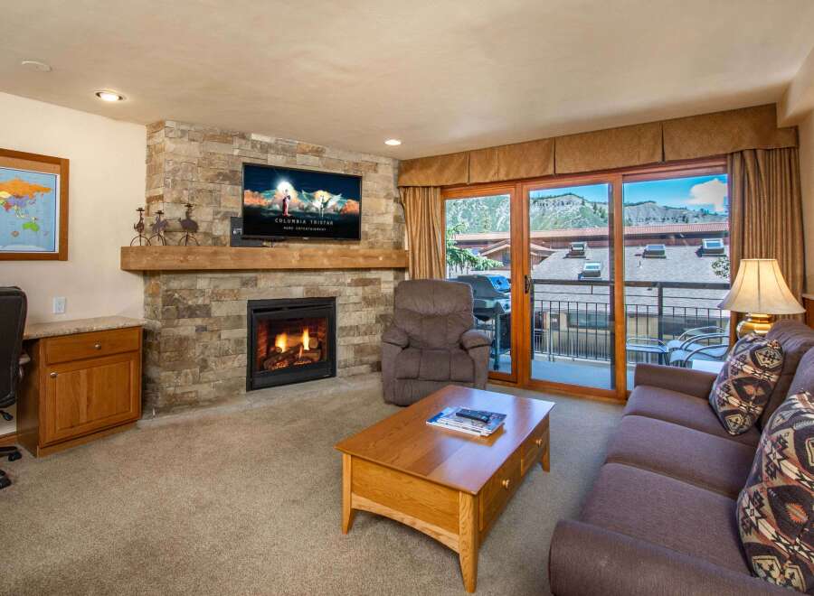 Cozy living room featuring a stone fireplace with a mounted TV and a comfortable recliner.