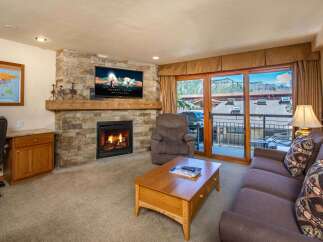Cozy living room featuring a stone fireplace with a mounted TV and a comfortable recliner.