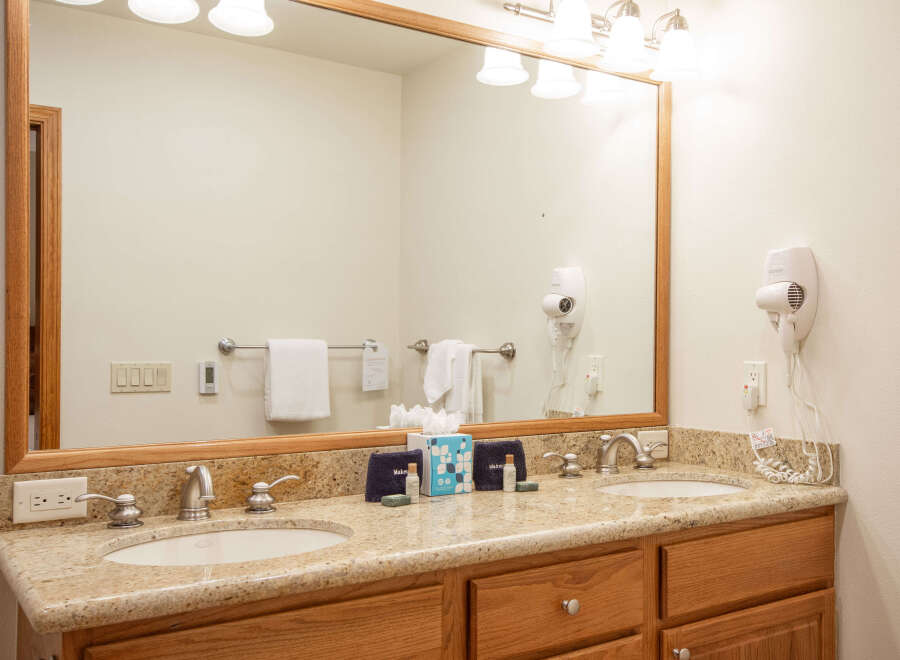 This spacious bathroom features a double vanity with granite countertops and modern chrome fixtures, perfect for any morning routine.