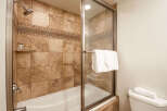 Experience luxury in this beautifully appointed bathroom featuring a spacious bathtub and shower combination enclosed by a sleek glass door.