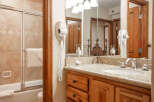 This charming bathroom features a spacious bathtub with a sliding glass door and a convenient wall-mounted hairdryer.