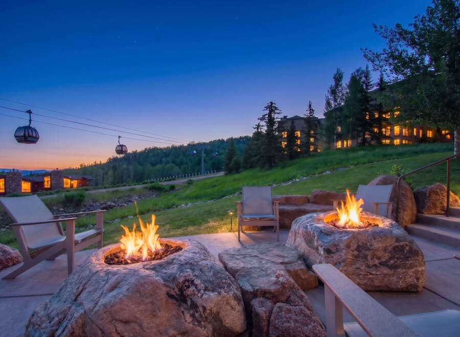 Experience luxury mountain living with this stunning outdoor patio featuring natural stone fire pits and comfortable seating.
