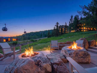 Experience luxury mountain living with this stunning outdoor patio featuring natural stone fire pits and comfortable seating.