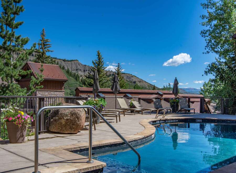 Escape to this mountain oasis featuring a sparkling blue swimming pool and ample lounge chairs for ultimate relaxation.