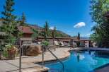 Escape to this mountain oasis featuring a sparkling blue swimming pool and ample lounge chairs for ultimate relaxation.