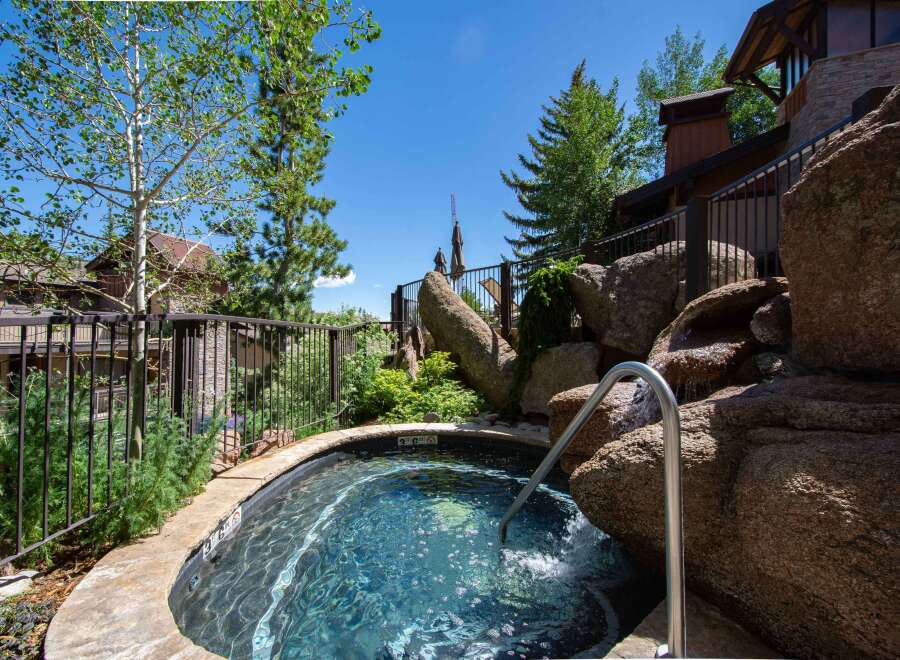 Indulge in ultimate relaxation with this stunning outdoor hot tub, featuring a natural rock waterfall and a sleek stainless steel handrail for easy access.