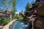 Indulge in ultimate relaxation with this stunning outdoor hot tub, featuring a natural rock waterfall and a sleek stainless steel handrail for easy access.