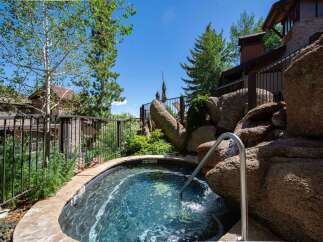 Indulge in ultimate relaxation with this stunning outdoor hot tub, featuring a natural rock waterfall and a sleek stainless steel handrail for easy access.