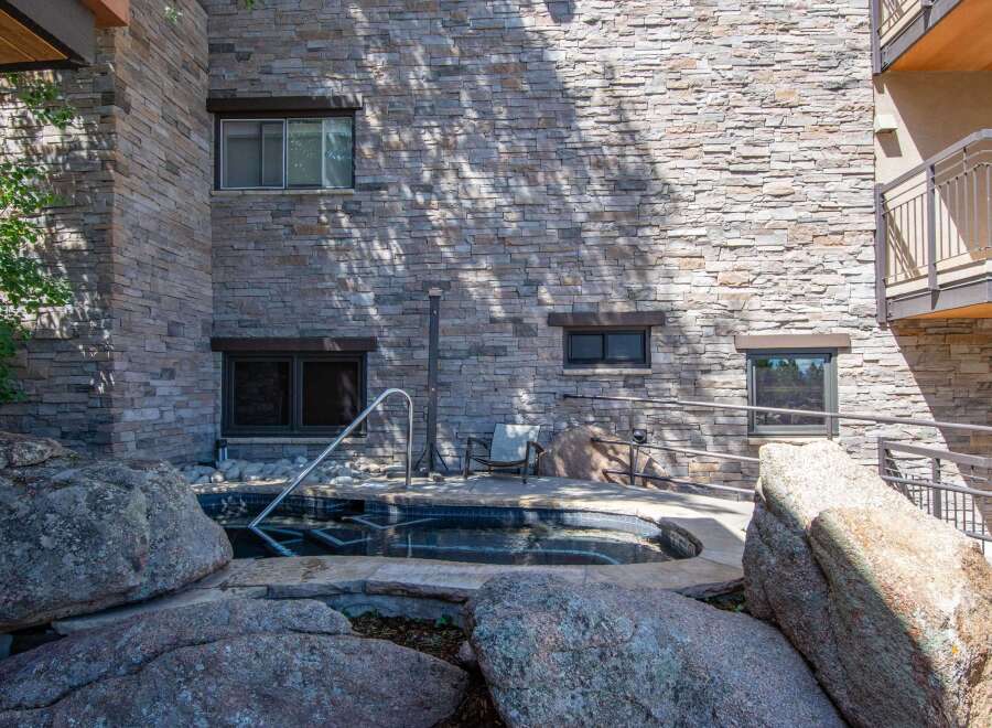 Experience ultimate relaxation in this luxurious outdoor spa, surrounded by natural stone and lush greenery.