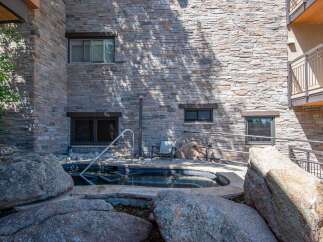 Experience ultimate relaxation in this luxurious outdoor spa, surrounded by natural stone and lush greenery.