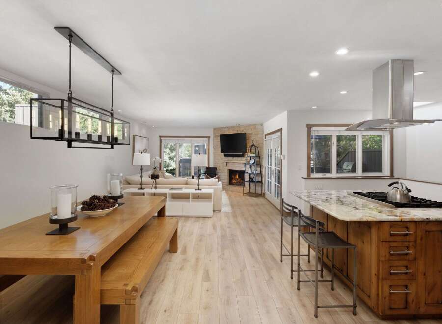 Experience open-concept living in this beautifully appointed home, featuring a spacious dining area with a modern chandelier and a cozy living room with a stone fireplace.
