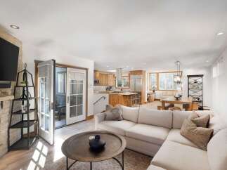 Experience modern living in this open-concept home featuring a spacious living area with a stone fireplace and a sleek entertainment center.