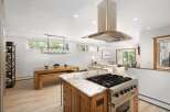 This spacious open-concept kitchen and dining area features a large island with a professional-grade gas range, perfect for culinary enthusiasts.