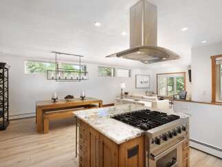 This spacious open-concept kitchen and dining area features a large island with a professional-grade gas range, perfect for culinary enthusiasts.