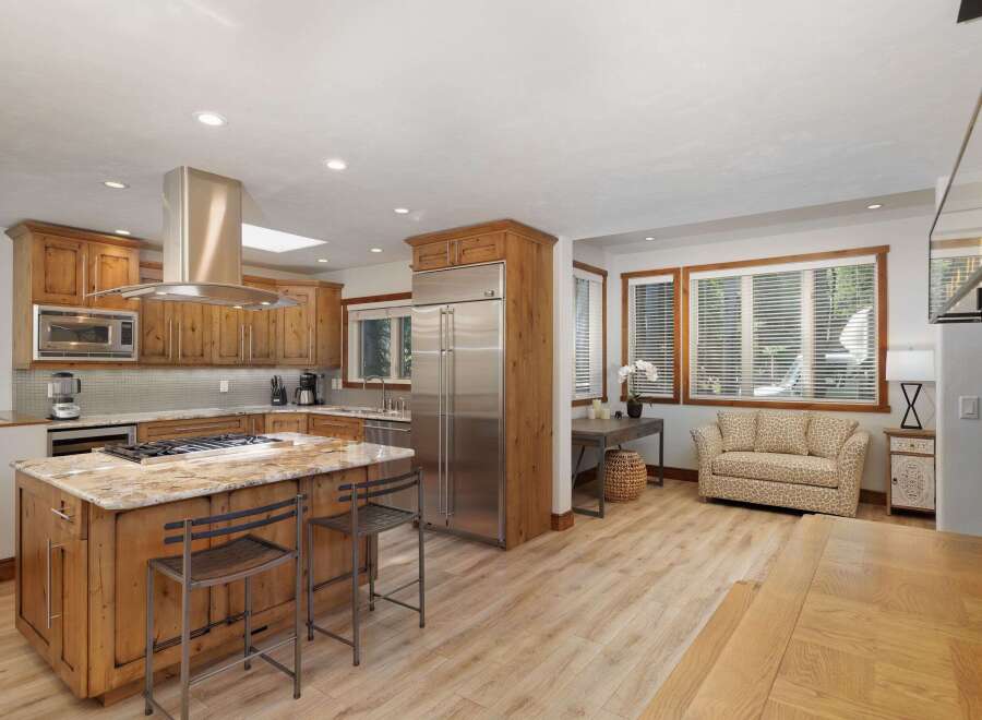 Experience rustic charm and modern convenience in this spacious kitchen, featuring custom wood cabinetry, a large granite island with bar seating, and high-end stainless steel appliances.