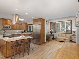 Experience rustic charm and modern convenience in this spacious kitchen, featuring custom wood cabinetry, a large granite island with bar seating, and high-end stainless steel appliances.