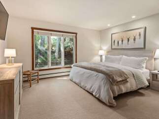 Experience serene mountain living in this beautifully appointed bedroom, featuring a plush king-sized bed with crisp white linens and a cozy throw.