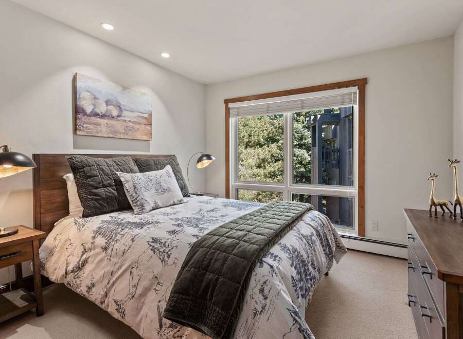 Experience serene mountain living in this charming bedroom, featuring a comfortable queen-size bed adorned with a nature-inspired duvet and plush pillows.