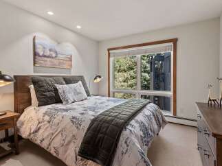 Experience serene mountain living in this charming bedroom, featuring a comfortable queen-size bed adorned with a nature-inspired duvet and plush pillows.