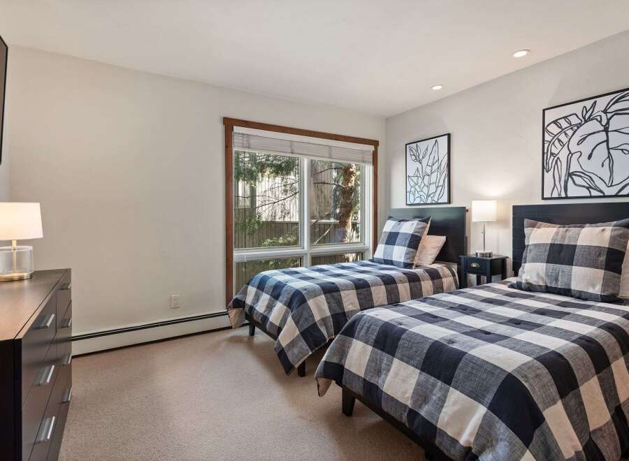 This charming bedroom features two twin beds with classic black and white buffalo check bedding, perfect for a cozy guest room or shared children's space.