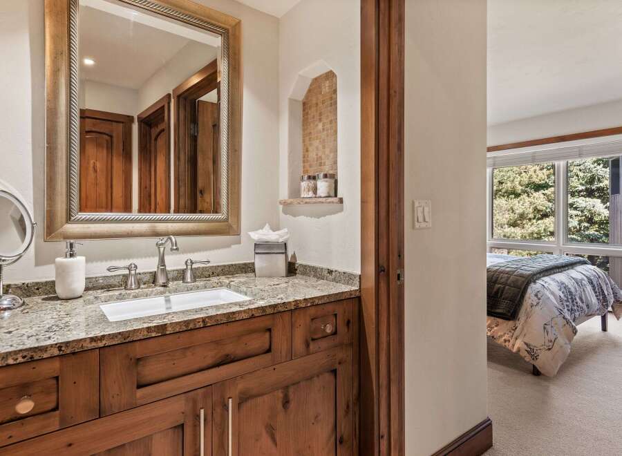 This charming bathroom features a double vanity with a granite countertop and a wooden cabinet base, complemented by a large ornate mirror.