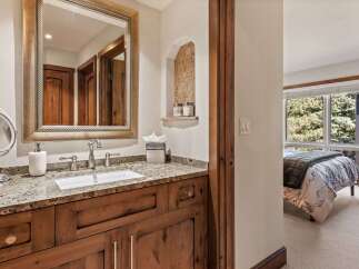 This charming bathroom features a double vanity with a granite countertop and a wooden cabinet base, complemented by a large ornate mirror.