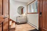 Step into this inviting entryway featuring warm wooden doors and stairs, complemented by a stylish console table with a unique antler-adorned mirror.