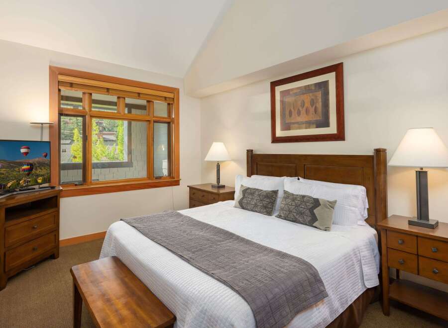 Experience comfort and style in this beautifully appointed bedroom, featuring a plush queen-size bed adorned with crisp white linens and decorative pillows.