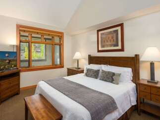 Experience comfort and style in this beautifully appointed bedroom, featuring a plush queen-size bed adorned with crisp white linens and decorative pillows.
