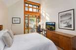 Experience modern comfort in this inviting bedroom, featuring a plush white quilted bed and a large, multi-pane window offering scenic views.