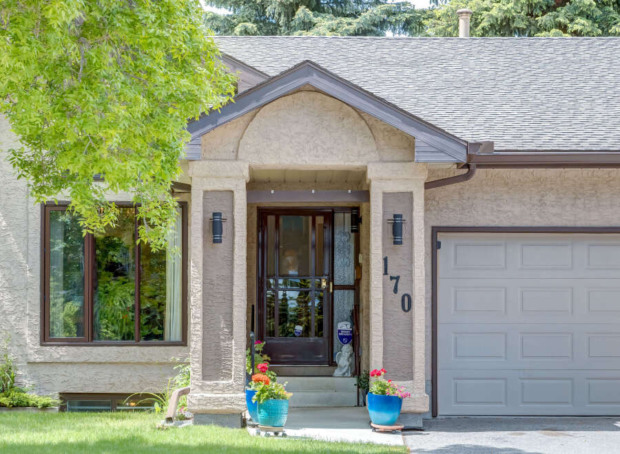 Charming home with a welcoming covered entryway featuring decorative pillars and exterior lighting.