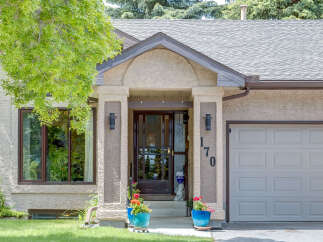 Charming home with a welcoming covered entryway featuring decorative pillars and exterior lighting.