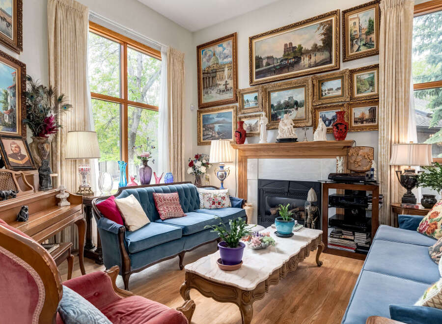 Step into this elegantly furnished living room, featuring a plush blue velvet sofa and a matching loveseat, perfect for relaxing.