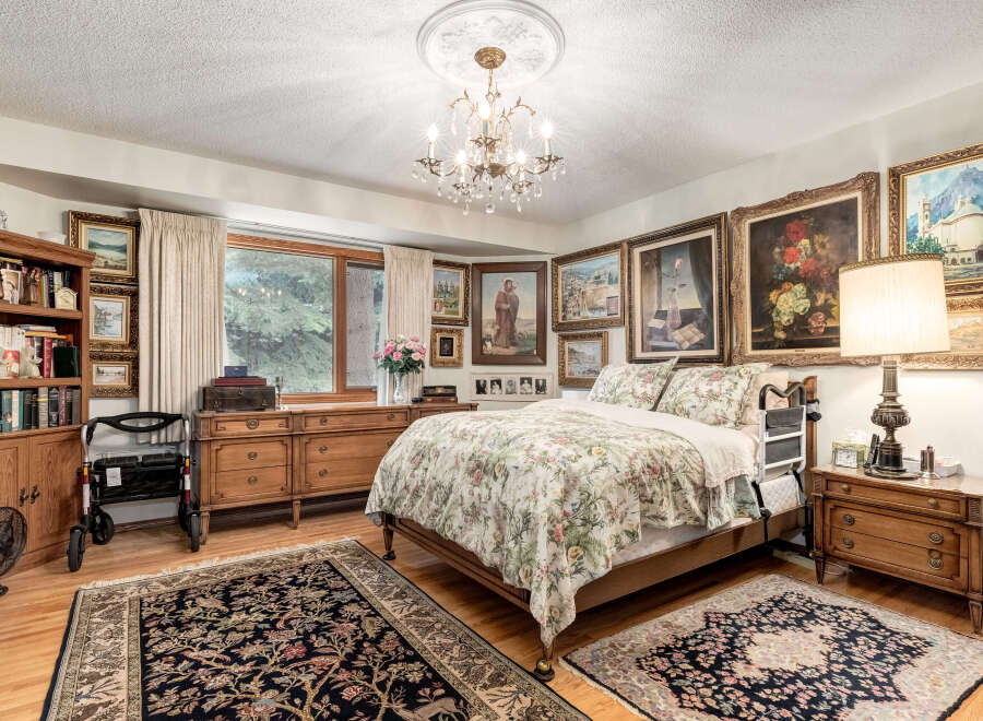 Step into this charming bedroom, featuring a luxurious floral comforter and elegant wooden furniture.