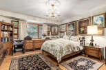 Step into this charming bedroom, featuring a luxurious floral comforter and elegant wooden furniture.
