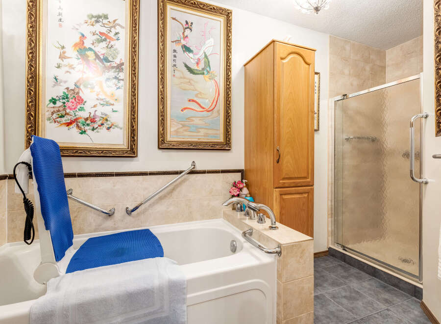 This accessible bathroom features a walk-in bathtub with a built-in lift and grab bars for enhanced safety and convenience.
