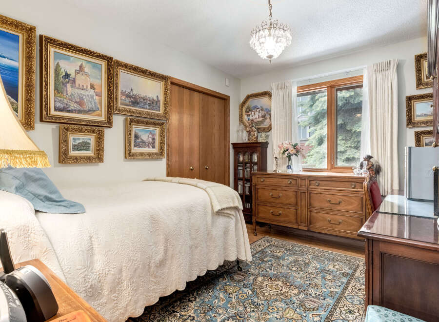 This charming bedroom features a comfortable bed adorned with a textured white quilt and a soft blue throw, complemented by a decorative fringed lamp.